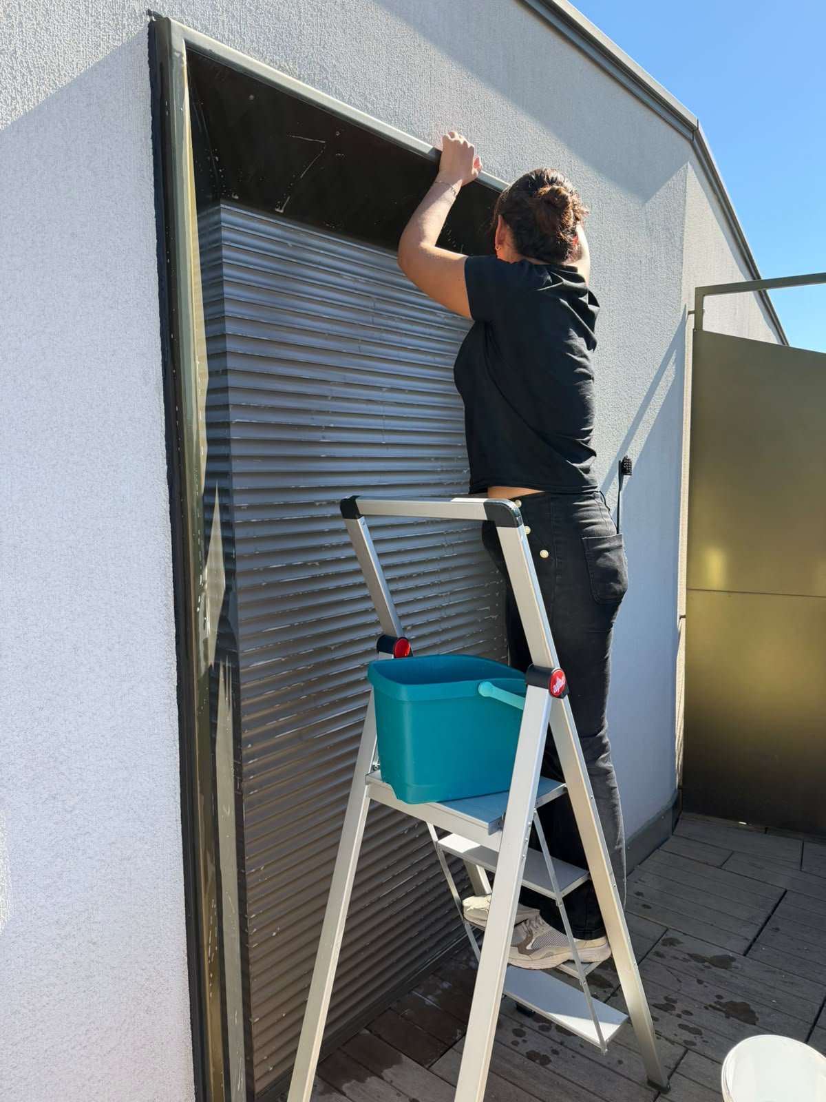 Nettoyage à la main de l’encadrement d’un store extérieur sur une terrasse