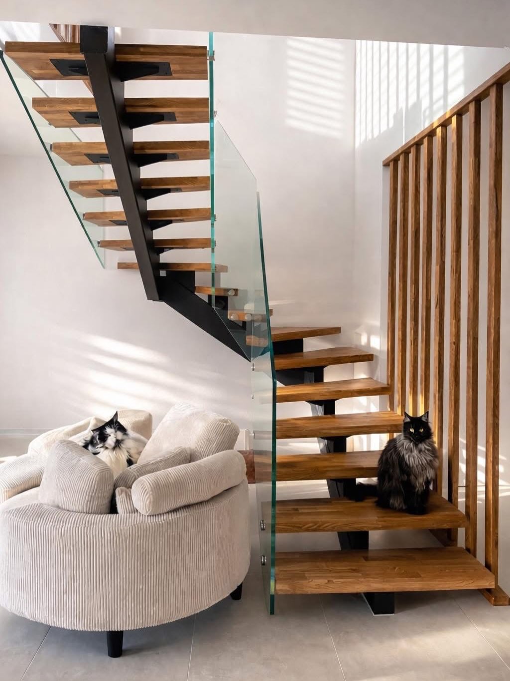 Escalier aux marches en bois, structure noire et garde-corps en verre dans un intérieur lumineux