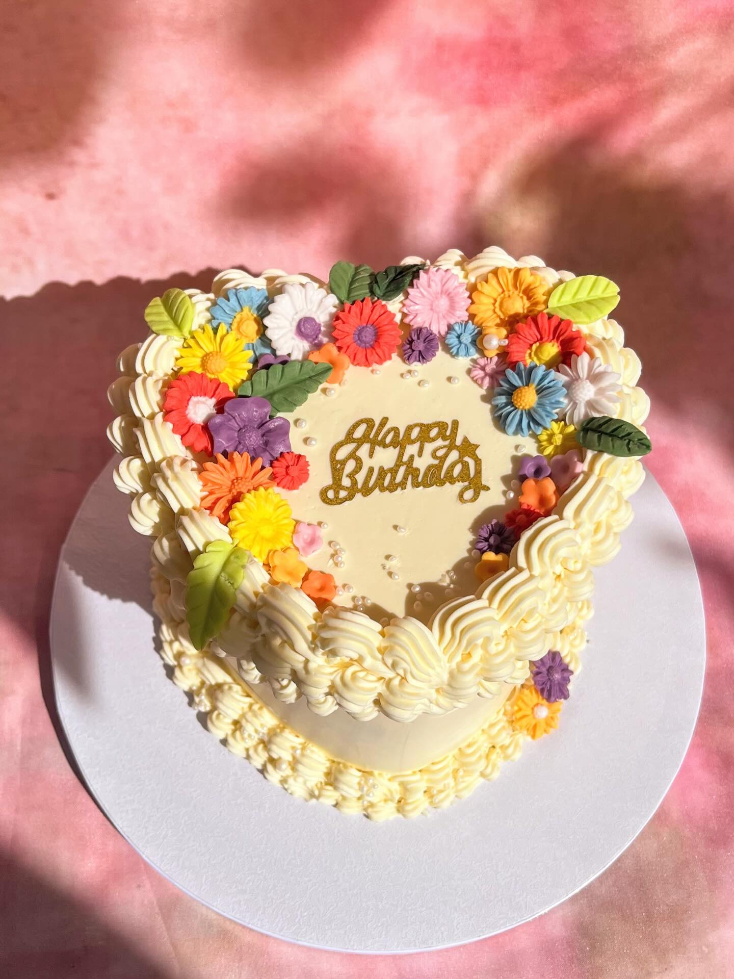 Gâteau d’anniversaire en forme de cœur, décoré à la main de fleurs multicolores