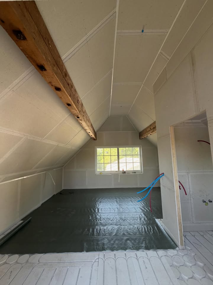 Aménagement de combles avec cloisons en plâtre, poutres apparentes et sol en préparation