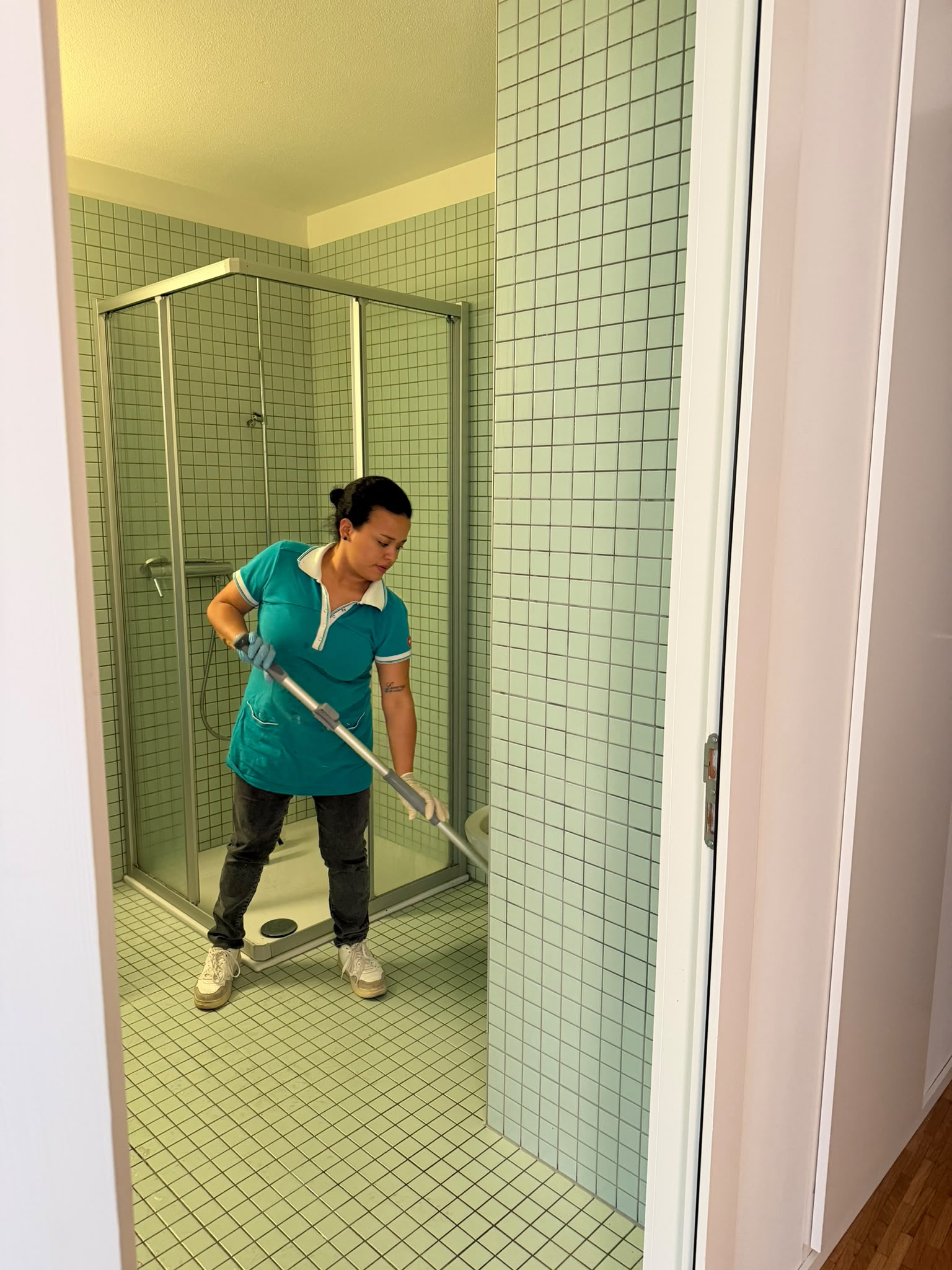 Une professionnelle entretient le sol carrelé d’une salle de bains