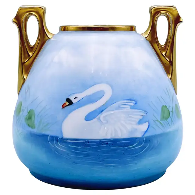 Rounded blue vase decorated with a white swan on water, with two open gold-toned handles and a gold-toned rim.